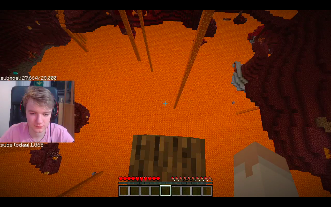 This is a screenshot from Tommy's stream. He stands on a single oak log over a lake of lava in the nether. He stares straight down at the lava pool tens of meters below him. His face cam shows him to be disintrested and bored.